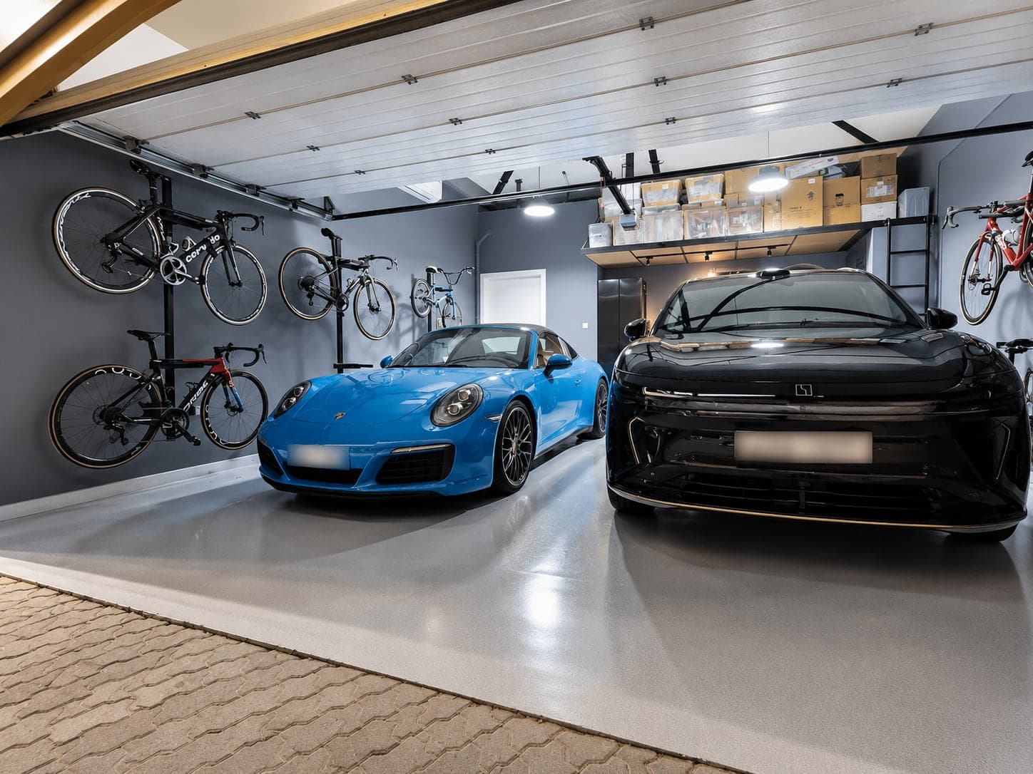 Two cars parked inside the finished G28 garage with bikes on the walls and storage overhead